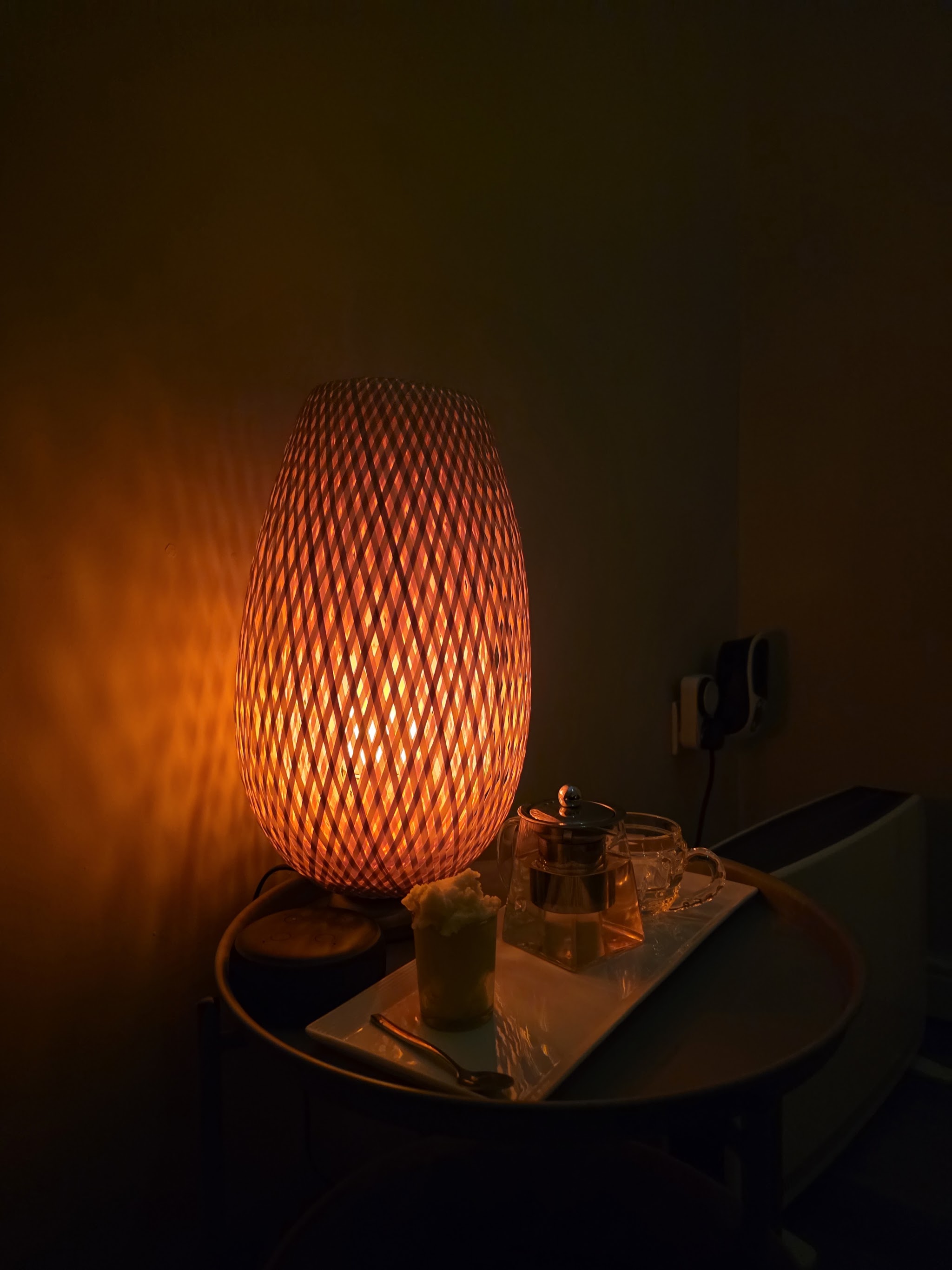 A woven lamp glowing beside a tea tray